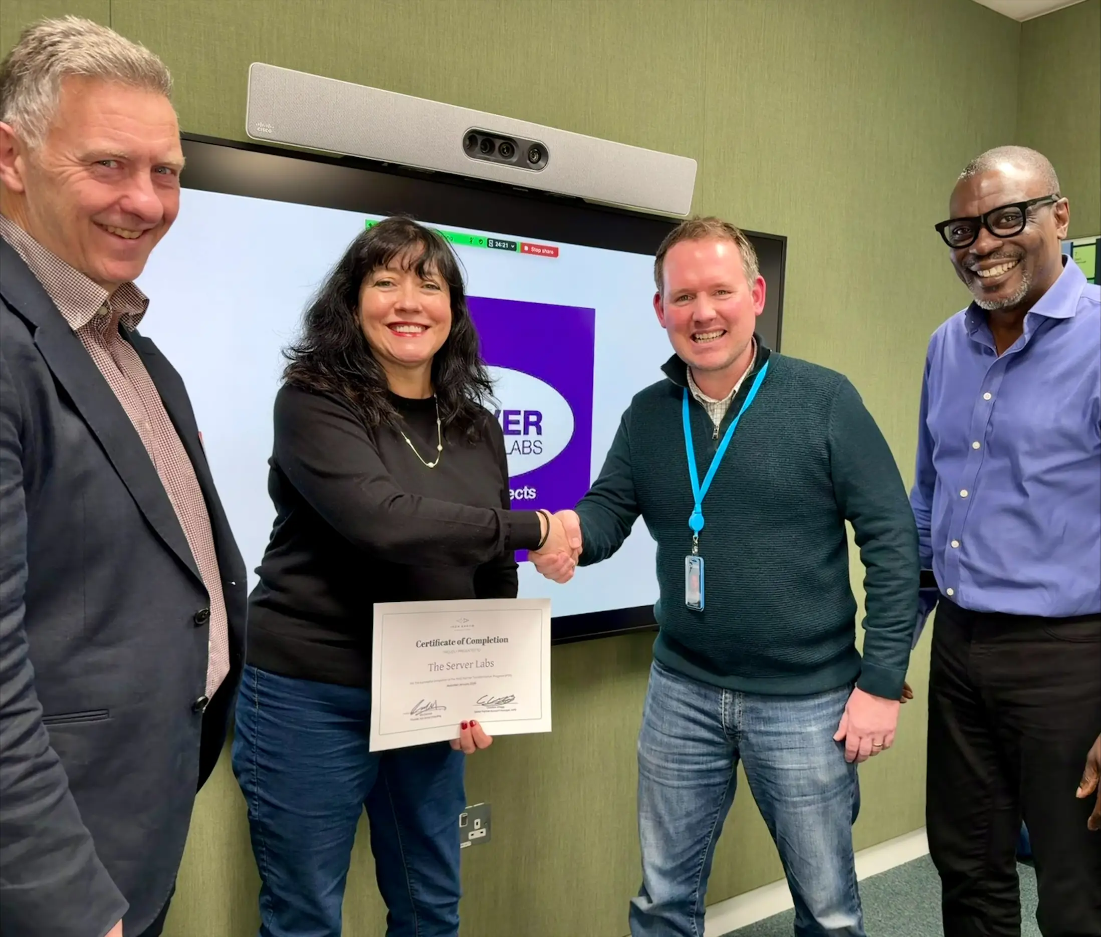 Four professionals shaking hands after certificate presentation