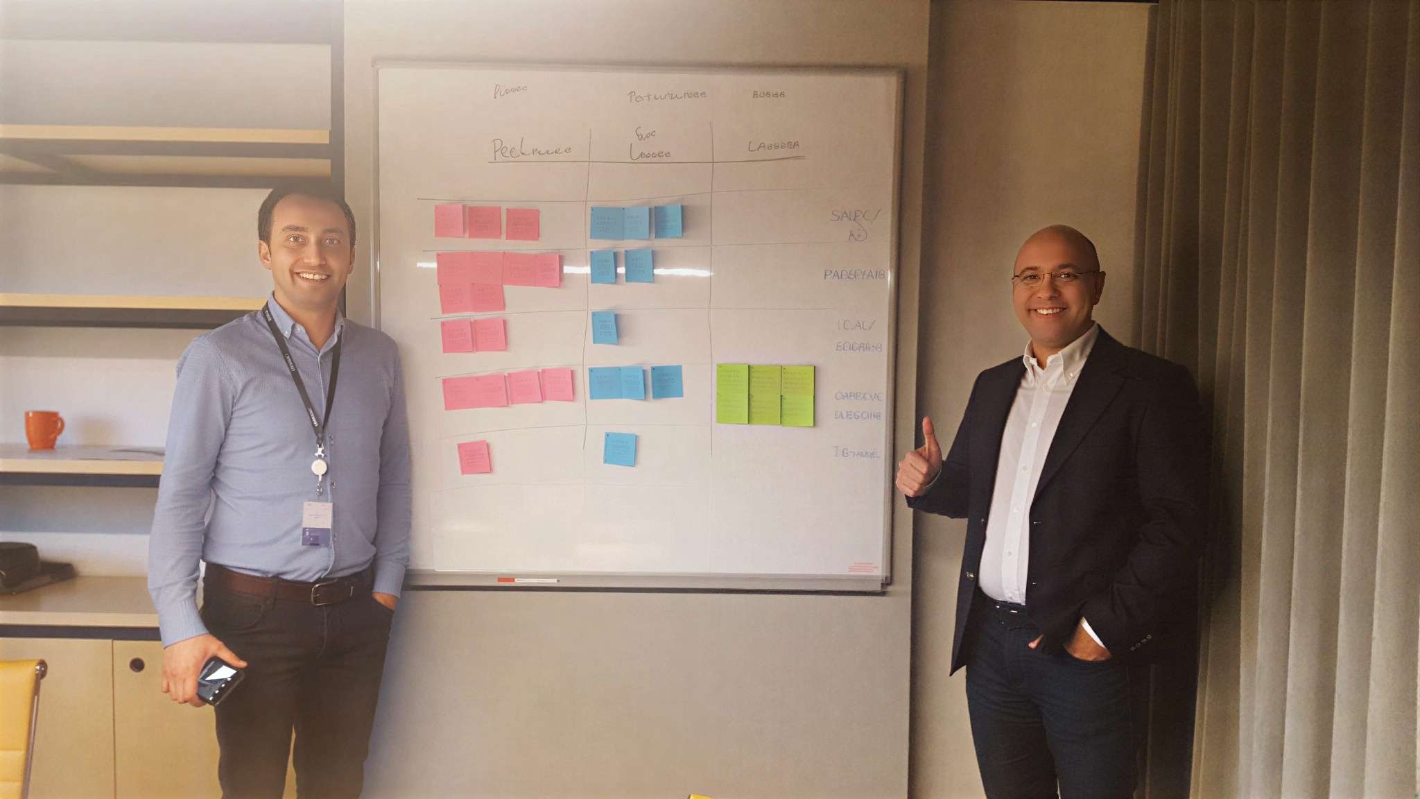 Two men standing beside whiteboard with colorful sticky notes